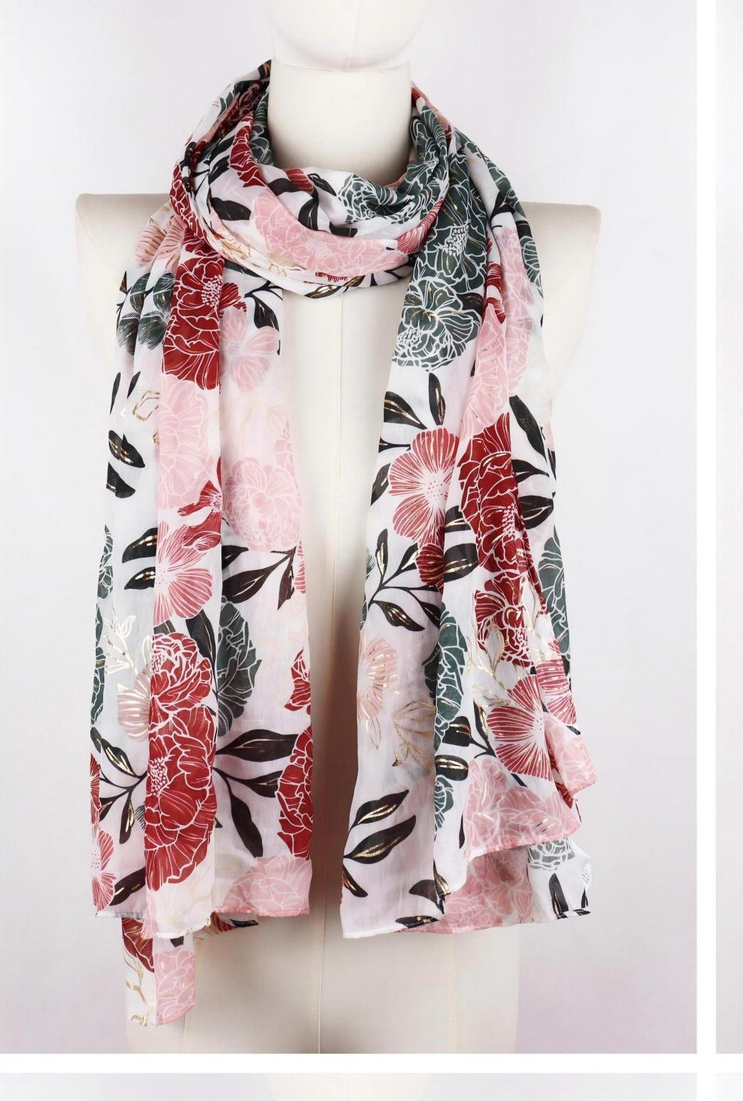 Long floral printed scarf with gold accents draped on mannequin